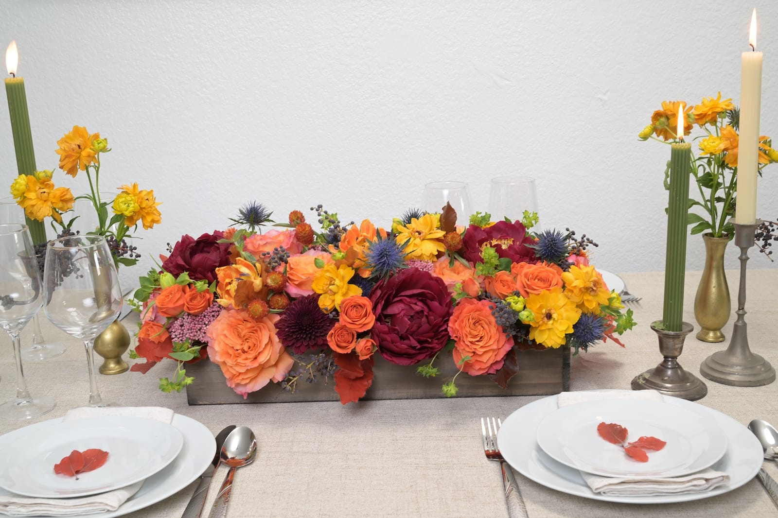 Autumn tablescape centerpiece with burnt orange roses, burgundy dahlias, dried flowers and taper candles