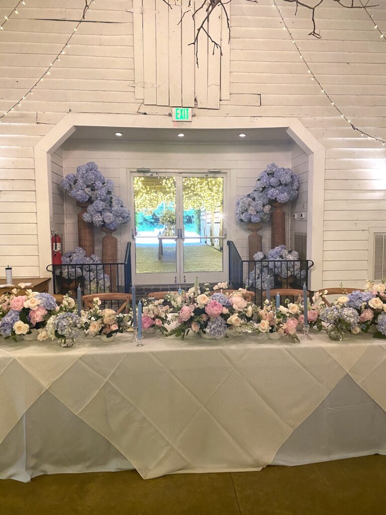 Elegant white and blush wedding table centerpiece with roses in a tall gold vase