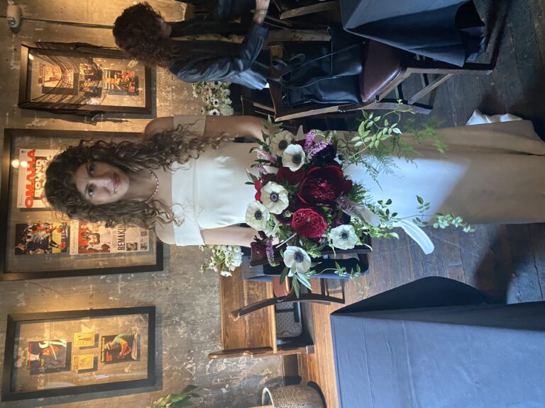 Bride holding a cascading wedding bouquet with white anemones, deep burgundy dahlias and trailing greenery designed by Hidden Door Floral Studio