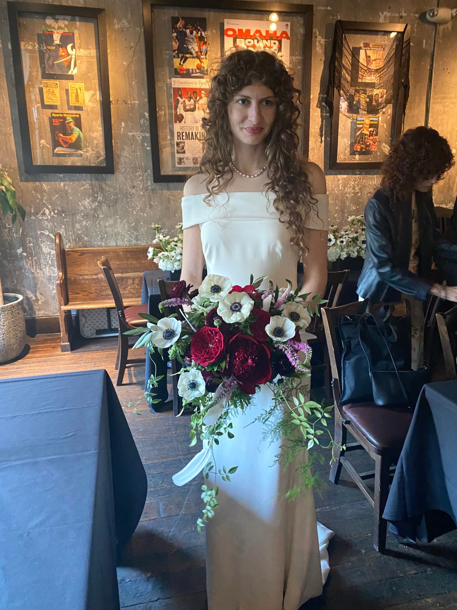 Bride holding a cascading wedding bouquet with white anemones, deep burgundy dahlias and trailing greenery designed by Hidden Door Floral Studio