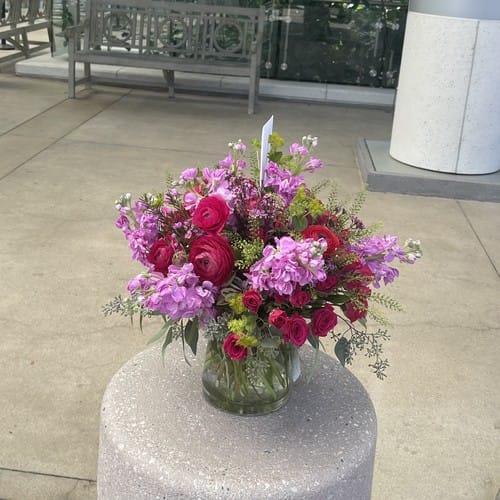 Vibrant pink peonies and garden roses in full bloom arranged in a glass vase during peak peony season in North Carolina - peony season north carolina