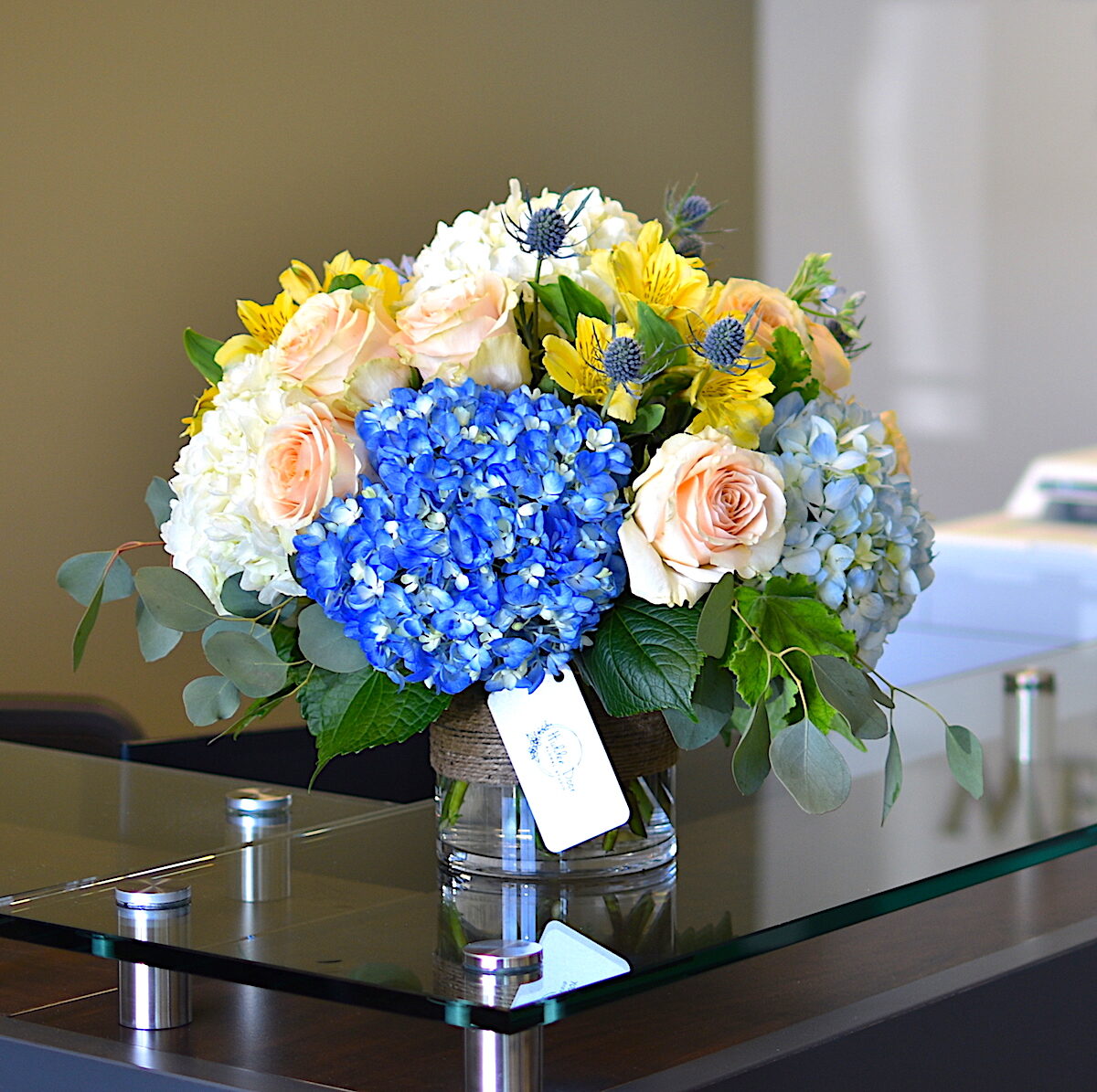 Business flower delivery in Raleigh: blue and white hydrangea with peach roses on an office reception desk