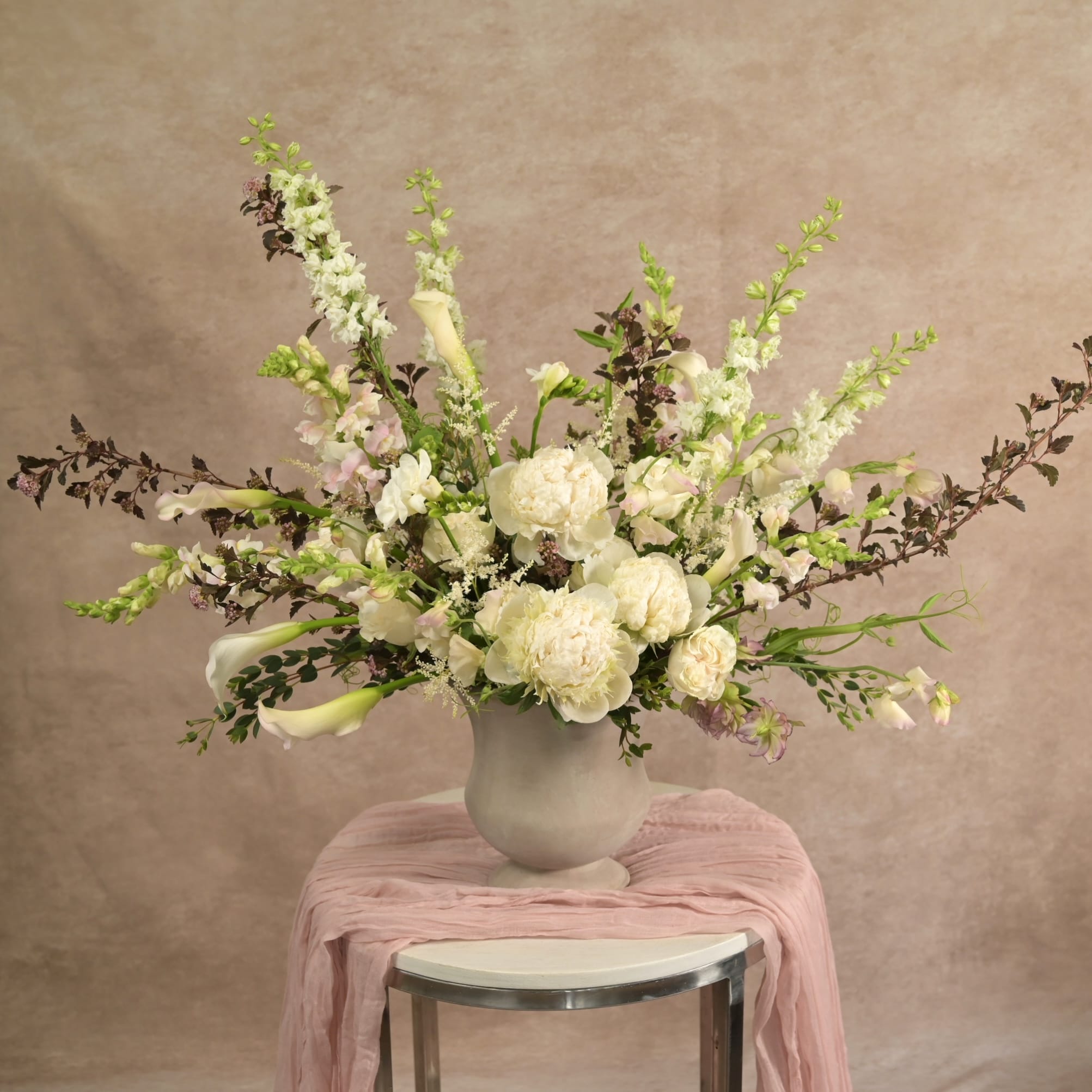 Elegant white peony and calla lily arrangement with snapdragons and dark foliage in a matte grey vase by Hidden Door Floral Studio Raleigh